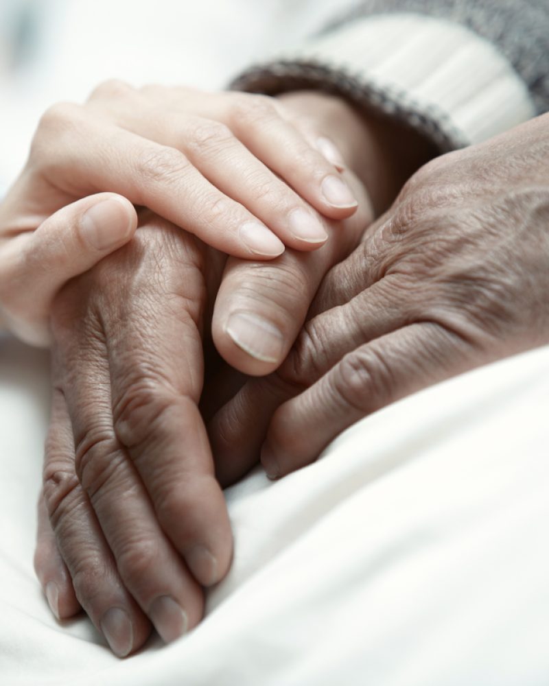 Hand of woman touching senior man in clinic